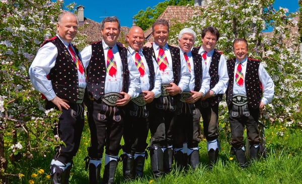 Musikgruppe Kastelruther Spatzen in traditioneller Tracht vor blühenden Bäumen