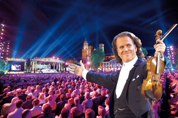 Dirigent mit Geige begrüsst ein grosses Publikum vor beleuchteter Open Air Bühne bei Nacht