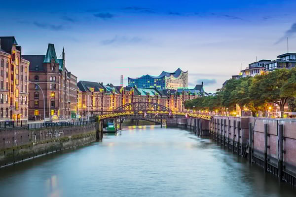 Abendliche Ansicht der Hamburger Speicherstadt mit beleuchteten Backsteingebäuden, Brücke über den Kanal und der Elbphilharmonie im Hintergrund