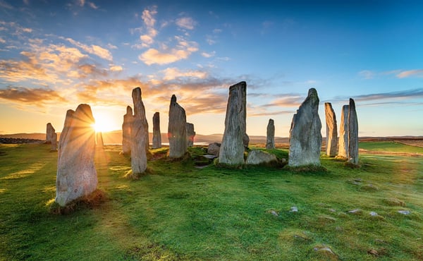 Steinkreis der Callanish Stones bei Sonnenuntergang auf grünem Hügelland