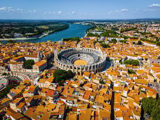 Luftaufnahme von Arles mit rotem Dachmeer und römischem Amphitheater im Zentrum