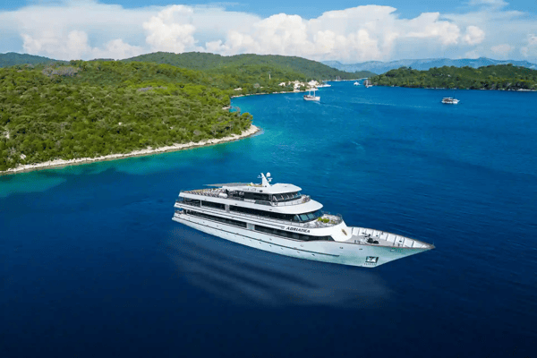 Yacht MS Adriatica fährt durch blaues Meer vor bewaldeter Küste