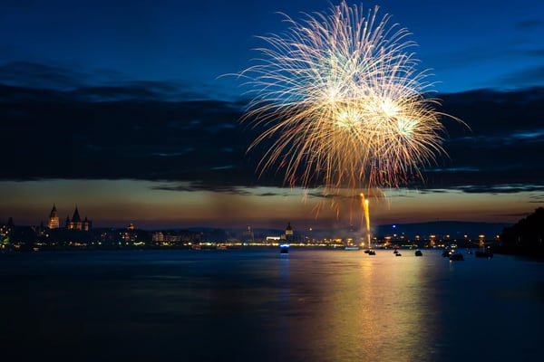 Grosses Feuerwerk erleuchtet den Nachthimmel über dem Rhein und einer beleuchteten Stadt