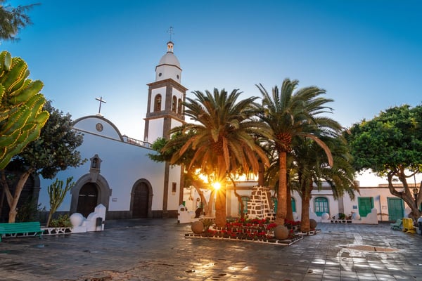 Kirche und Platz in Arrecife mit Palmen, weissen Gebäuden und Abendlicht