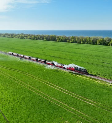 Historische Dampfbahn Molli fährt durch grüne Felder nahe der Ostseeküste