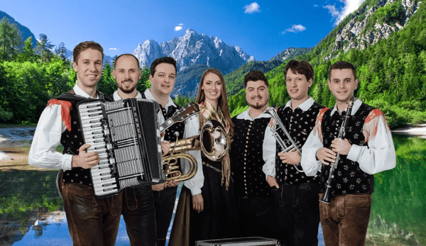 Musikgruppe in traditioneller Tracht mit Akkordeon Blechbläsern und Klarinette vor hellem Hintergrund